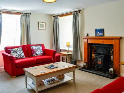 a living room with a red couch and a fireplace at Mullhill in Ardwell