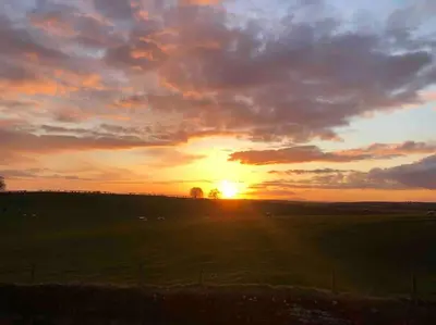 a sunset in a field with the sun setting at Kitty’s Place, Apartment, Eden Valley, Cumbria in Brampton