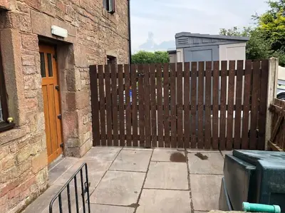 a wooden fence in front of a building at Kitty’s Place, Apartment, Eden Valley, Cumbria in Brampton