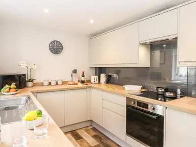 a kitchen with white cabinets and a counter top at Dovestones in Keswick