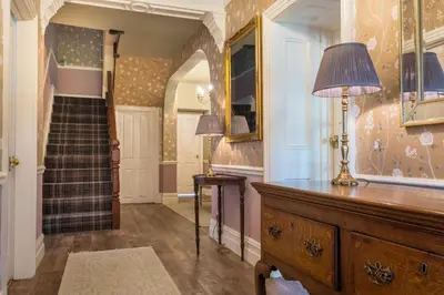 a hallway with a dresser with a lamp and a staircase at Swinside Lodge in Keswick