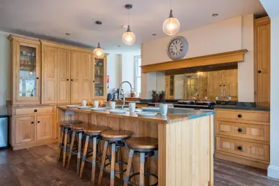 a kitchen with wooden cabinets and a large island with bar stools at Swinside Lodge in Keswick