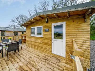 a wooden cabin with a table and a white door at Starling Lodge - Uk31071 in Westward