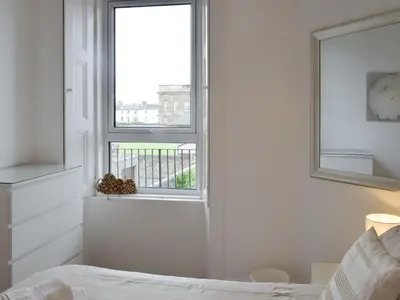 a white bedroom with a bed and a window at Charlotte Street in Ayr