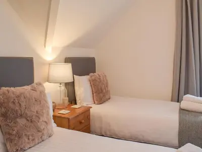 a bedroom with two beds and a lamp on a night stand at Southcroft Lodge in Whiting Bay