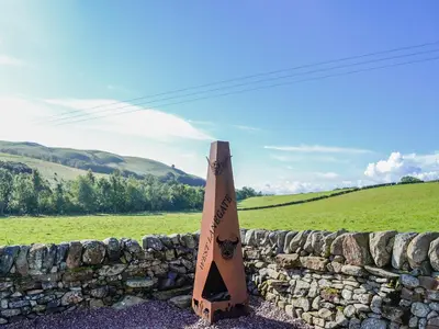 a wooden sign sitting next to a stone wall at West Lanegate Farmhouse in Amisfield Town