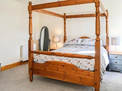 a bedroom with a wooden bed with a wooden frame at West Lanegate Farmhouse in Amisfield Town