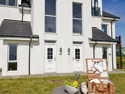 a white house with a basket of fruit in front of it at Seaviews And Hot Tub At The Fairways - Uk39821 in Portpatrick