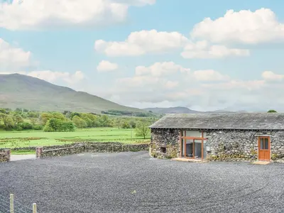 a stone house with a gravel driveway at Doddick Beck - Uk39153 in Threlkeld