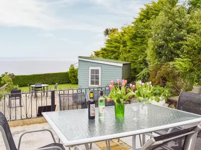a table with two bottles of wine and flowers on a balcony at Seacliffe in Kildonan
