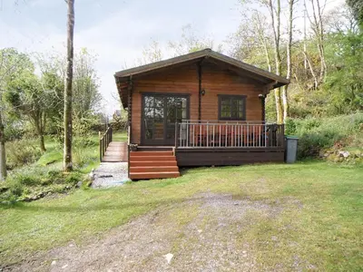 a log cabin with a porch and stairs in a yard at Auchenhill Lodge in Lochend