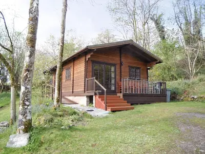 a log cabin in the woods with a porch and stairs at Auchenhill Lodge in Lochend