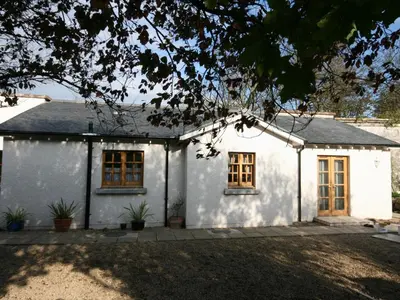 a white house with two windows and a driveway at Gardener's Cottage in Girvan