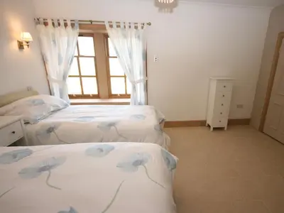 a bedroom with two beds and a window at Gardener's Cottage in Girvan