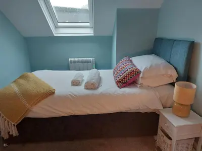 a bedroom with a bed with two pillows and a window at Hill Street Cottage in Portpatrick