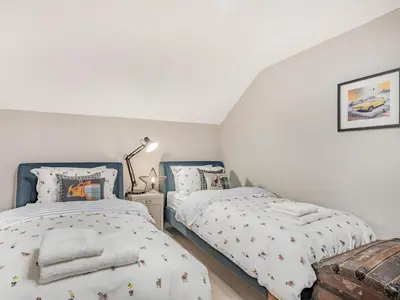 two beds in a bedroom with white walls at Keepers Cottage in Durisdeer