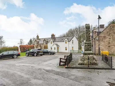 a parking lot with cars parked in front of a house at Keepers Cottage in Durisdeer