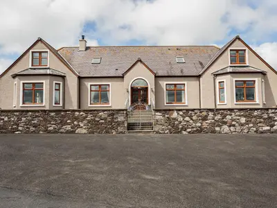a large house with a stone wall at Kringlands in Stranraer