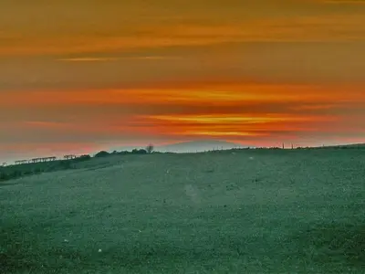 a sunset over a field with a mountain in the background at Halliday Hill Cottage in Dalton