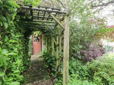 a wooden archway in a garden with a red door at The Lodge in Penrith