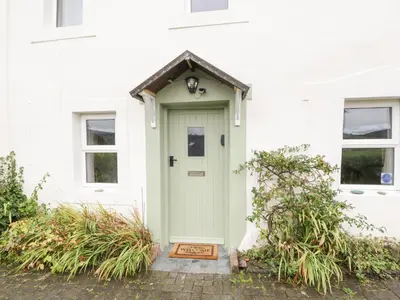a white house with a green door at Fellside Cottage in Cockermouth