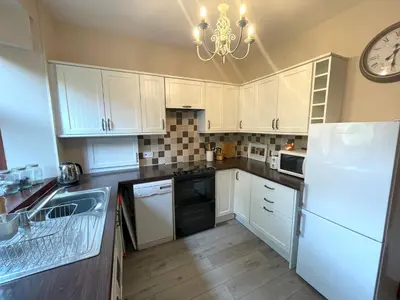 a kitchen with white cabinets and a clock on the wall at Beautiful Apartment - Outstanding Central Location - Pass the Keys in Dumfries