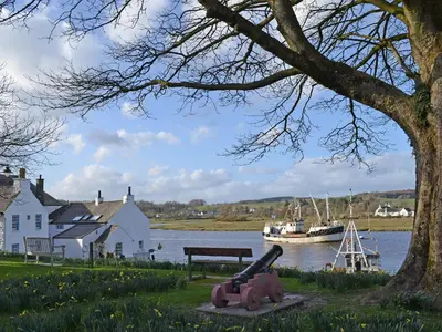 a bench next to a body of water with a boat at Number 7 in Gatehouse of Fleet