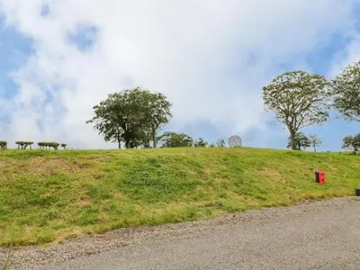 a grassy hill with trees and a red box on it at Laird Lodge 4 in Lockerbie