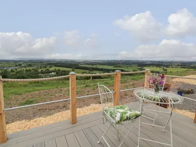 a balcony with two chairs and a view of the countryside at Laird Lodge 1 in Lockerbie