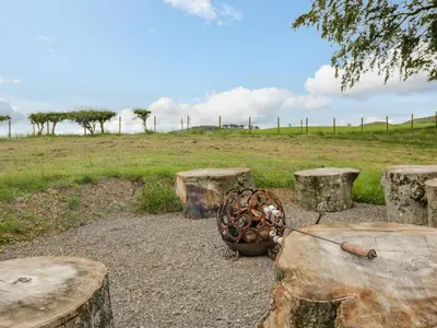 a group of picnic tables and logs with a field at Laird Lodge 1 in Lockerbie