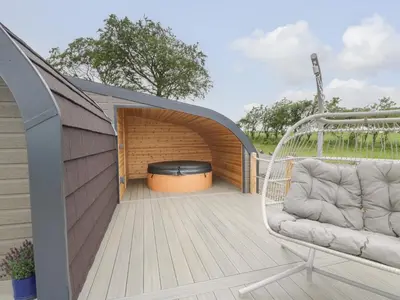 a deck with a swing and a fire pit at Laird Lodge 1 in Lockerbie