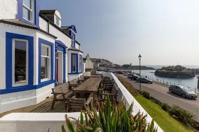 a wooden table and benches on a balcony of a building at The Knowe in Portpatrick