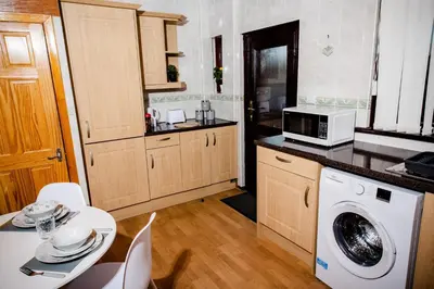 a kitchen with a washing machine and a microwave at Rigside House in Douglas