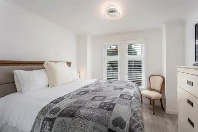 a white bedroom with a bed and a chair at 9A Millbrae - Donnini Apartments in Ayr