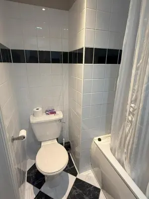 a white bathroom with a toilet and a tub and a sink at Chase Hotel in Whitehaven