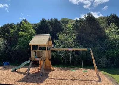a wooden playground with a swing set in a park at Bennane Shore Holiday Park in Lendalfoot