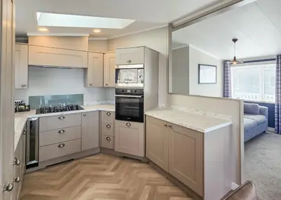a kitchen with white cabinets and a stove top oven at Bennane Shore Holiday Park in Lendalfoot