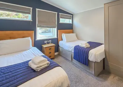 a small bedroom with two beds and two windows at Bennane Shore Holiday Park in Lendalfoot