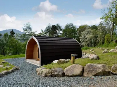 a small building on a gravel road with rocks at Lowside Farm Glamping in Troutbeck