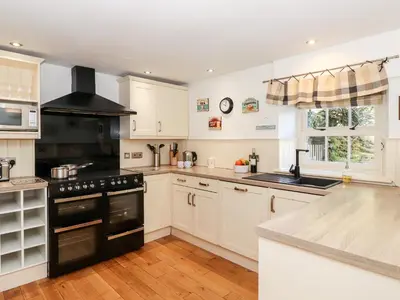 a kitchen with white cabinets and a black stove top oven at Huntingstile Lodge in Ambleside