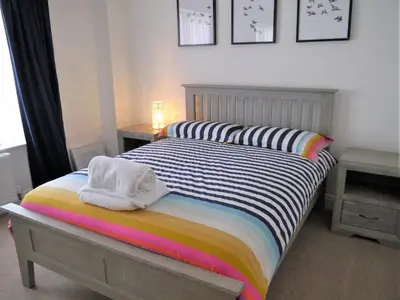 a bedroom with a bed with a striped comforter at Driftwood in Kippford