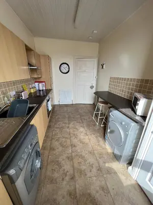 a kitchen with a washing machine and a clock on the wall at Dalblair Apartment in Ayr