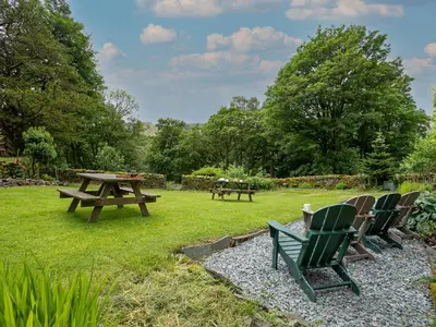 a group of chairs and a picnic table in the grass at Little How in Ambleside