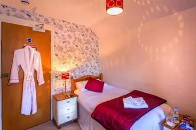 a bedroom with a bed and a robe hanging on a wall at Neptunes Rest Guest Hotel in Stranraer