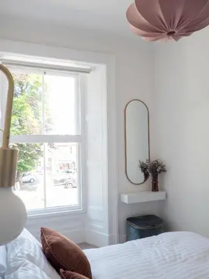 a bedroom with a bed and a mirror and a window at Coorie Away - Kirkcudbright in Kirkcudbright
