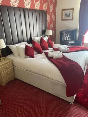a bedroom with a large bed with red pillows at George Hotel in Keswick