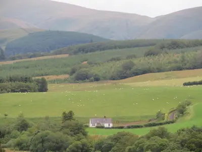 a large green field with a house in the middle at Marr Cottage in Thornhill