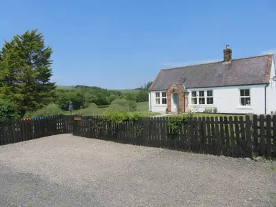 a fence in front of a white house at Marr Cottage in Thornhill