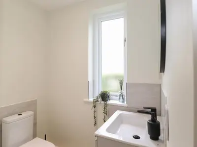 a bathroom with a white sink and a window at Fran's Nest in Keswick