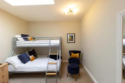 a bedroom with two bunk beds and a chair at Arran View Apartment at Heads of Ayr in Ayr